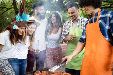 Barbekü yapma ve doğada yemeğe mutlu arkadaşlar
