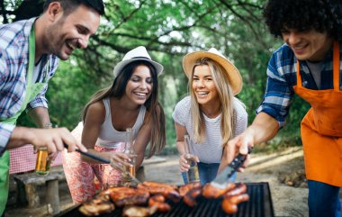 Açık havada barbekü akşam yemeği bira içme ve yemek yeme mutlu arkadaş grubu