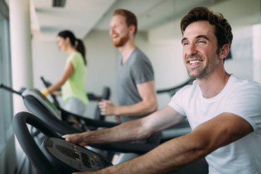 Spor salonunda koşu bandında egzersiz yapan bir grup arkadaş.