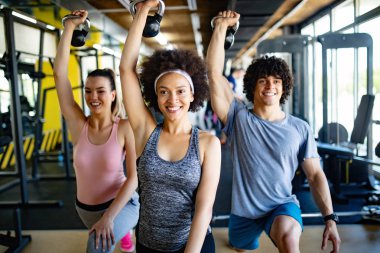 Spor salonunda egzersiz yapan bir grup mutlu genç.