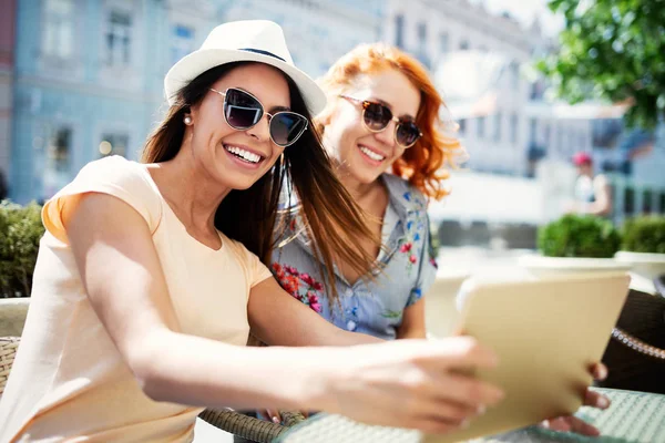 İki mutlu genç kadın dijital tablet kafede açık kullanma