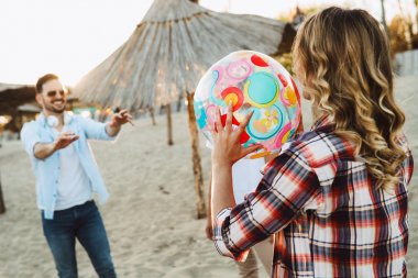Grup genç neşeli arkadaşıyla kumsalda topla oynamayı