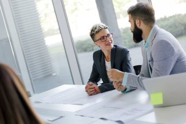 Takım inşaat planları üzerinde birlikte çalışan mimarlar