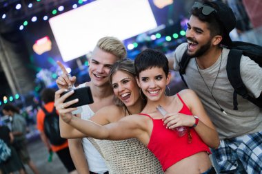 Mutlu genç arkadaşlar müzik festivalinde eğleniyor.