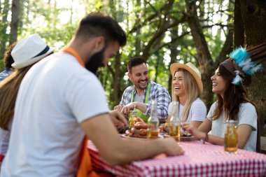 Açık havada barbekü akşam yemeği bira içme ve yemek yeme mutlu arkadaş grubu