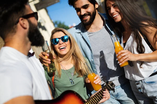 Bir grup arkadaş dışarıda gitar çalarak yaz gününün tadını çıkarıyorlar. Mutlu gençler birlikte iyi vakit geçiriyorlar.