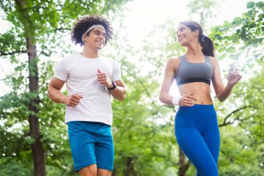 Mutlu genç kadın bir parkta açık egzersiz yapıyor, koşu