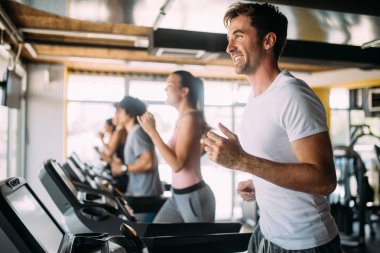 Spor salonunda koşu bandında koşan bir grup genç