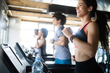 Spor salonunda egzersiz yapan bir grup mutlu fit insan.