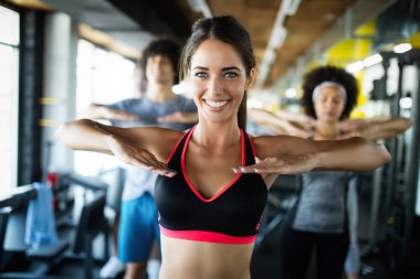 Spor salonunda egzersiz yapan bir grup mutlu genç.