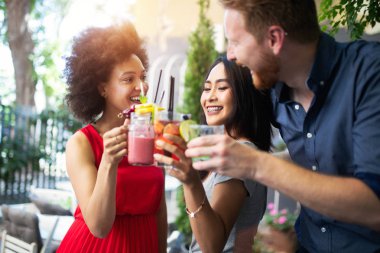 Çeşitli mutlu arkadaşlar yaz aylarında kafede eğleniyor, konuşuyor, gülümsüyor.