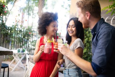 Çeşitli mutlu arkadaşlar yaz aylarında kafede eğleniyor, konuşuyor, gülümsüyor.