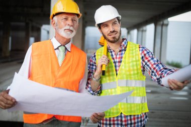 Mimarlar ve mühendislerden oluşan kendinden emin bir ekip modern inşaat alanında birlikte çalışıyor.