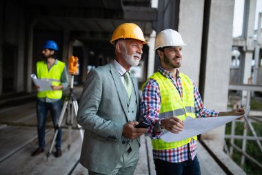 Mimarlar ve mühendislerden oluşan kendinden emin bir ekip modern inşaat alanında birlikte çalışıyor.