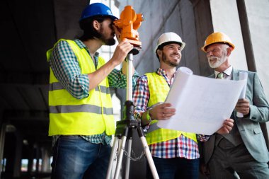 Mimarlar ve mühendislerden oluşan kendinden emin bir ekip modern inşaat alanında birlikte çalışıyor.