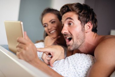 Mutlu çift aşık evde pijamayla tablet kullanma