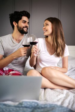 Evde dizüstü bilgisayar kullanarak gülümseyen mutlu çift