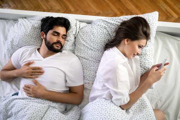 Beautiful Young Wife Texting Lover Smartphone While Husband Sleeping — Stock Photo, Image