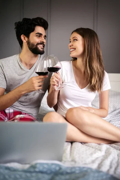 Evde dizüstü bilgisayar kullanarak gülümseyen mutlu çift