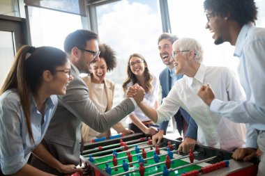 İş arkadaşları ofiste masa futbolu oynuyor.