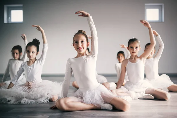 Group of fit little ballerinas doing exercises in dance school