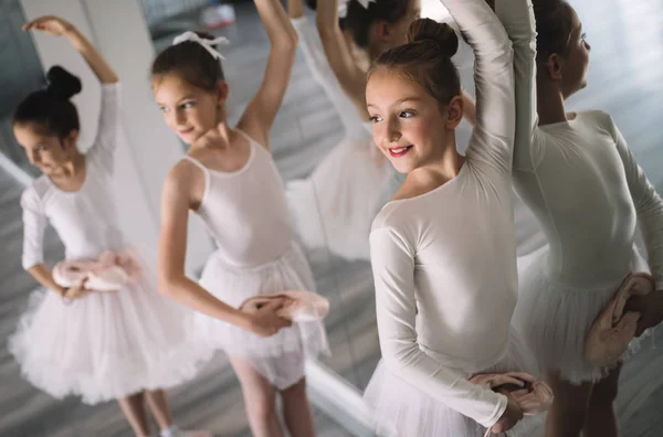 Group of fit little ballerinas doing exercises in dance school