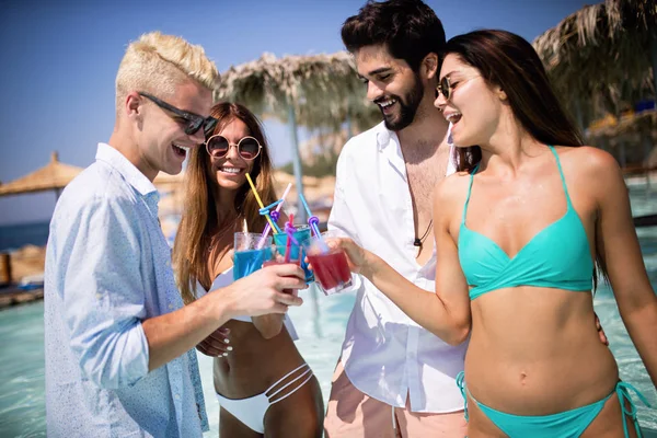 Bir grup mutlu arkadaş havuzda kokteyllerle dans ediyor.
