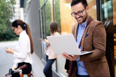 Genç ve mutlu iş adamlarına bakın dışarıda konuşuyorlar ve gülümsüyorlar.