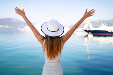 Güzel esmer genç kadın elbise ve şapka giyiyor, dışında gülümseyen