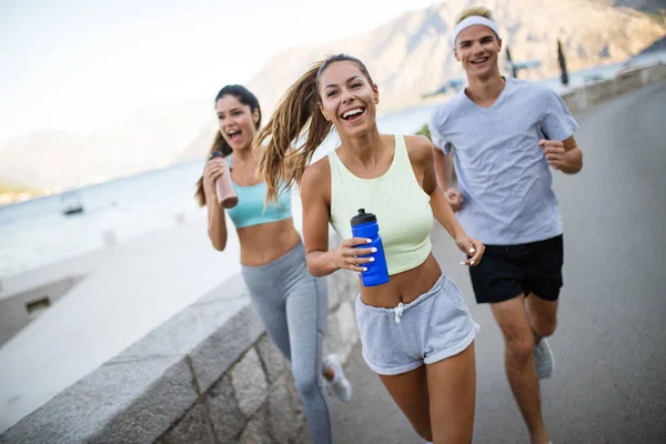 Gente feliz en forma corriendo y corriendo juntos en la naturaleza soleada de verano —  Fotos de Stock