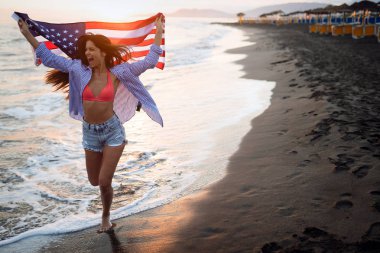 Mutlu kadın gülümseyip plajda koşarken bağımsızlık gününü kutluyor ve Amerika 'da özgürlüğün tadını çıkarıyor.