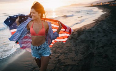 Mutlu kadın gülümseyip plajda koşarken bağımsızlık gününü kutluyor ve Amerika 'da özgürlüğün tadını çıkarıyor.