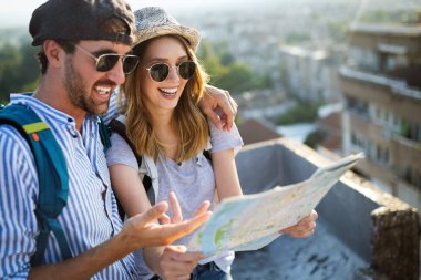 Happy young couple on vacation sightseeing city with map clipart