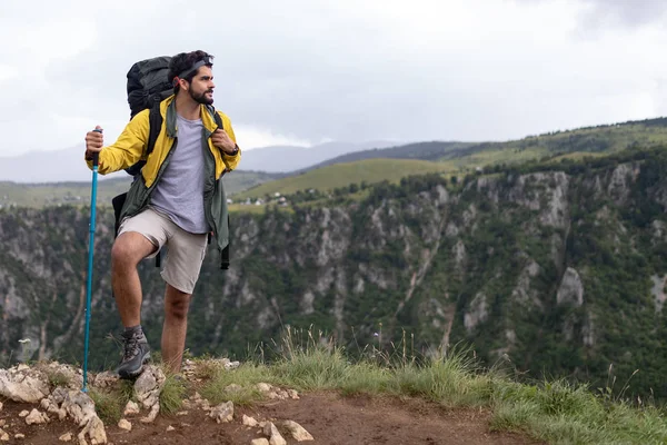 Happy man traveling with backpack hiking in mountains