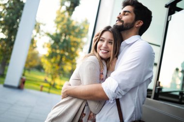 Mutlu genç çift dışarıda sarılıp gülüyor.