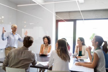 Ofiste iş arkadaşlarıyla birlikte çalışan ve iletişim kuran bir grup iş adamı.