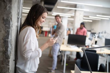 Ofiste iş arkadaşlarıyla birlikte çalışan ve iletişim kuran bir grup iş adamı.