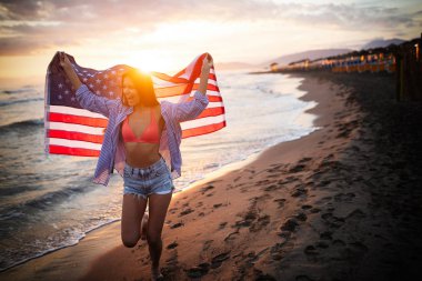 Mutlu kadın gülümseyip plajda koşarken bağımsızlık gününü kutluyor ve Amerika 'da özgürlüğün tadını çıkarıyor.