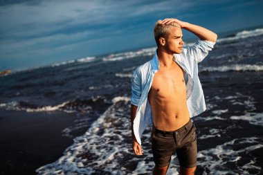 Tatildeyken deniz plajında duran yakışıklı genç adam