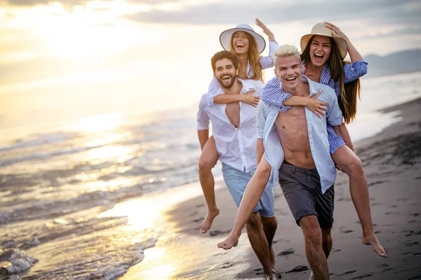 Glada Pojkvänner Piggyback Sina Flickvänner Vid Solnedgången Stranden — Stockfoto