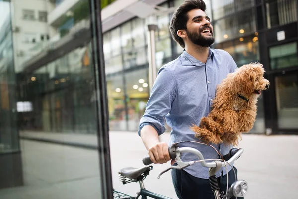 Happy handsome man holding dog in hands outdoors in city