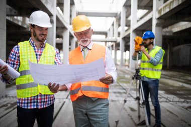 Mühendis, ustabaşı ve işçi inşaat alanında tartışıyor ve çalışıyor.