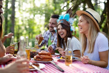 Açık havada barbekü akşam yemeği bira içme ve yemek yeme mutlu arkadaş grubu