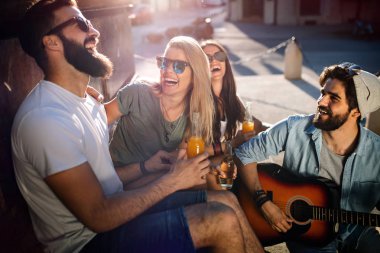 Bir grup arkadaş dışarıda gitar çalarak yaz gününün tadını çıkarıyorlar. Mutlu gençler birlikte iyi vakit geçiriyorlar.