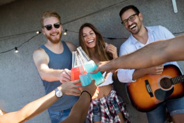 Bir çatı partisinde eğlenen, gitar çalan, şarkı söyleyen, dans eden ve sakinolan genç arkadaşlar