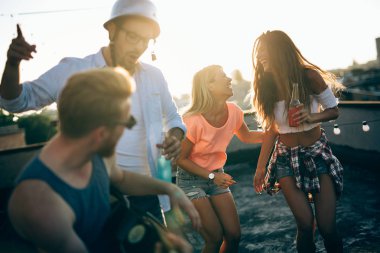 Bir çatı partisinde eğlenen, gitar çalan, şarkı söyleyen, dans eden ve sakinolan genç arkadaşlar