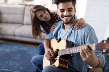Genç yakışıklı adam güzel kız arkadaşı için gitar çalıyor.