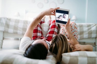 Genç mutlu çift yatak odasında dijital tablet kullanma