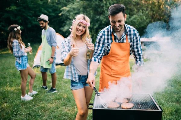 若い女性と男はキャンプ場で笑顔とローストバーベキューを作ります — ストック写真