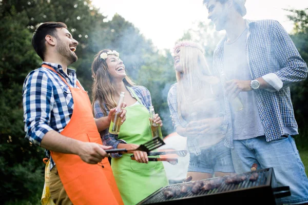 Gruppe Venner Der Har Udendørs Grill Griner Sammen - Stock-foto